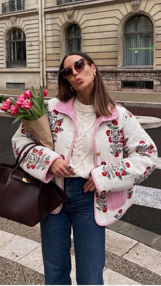 Woman in a floral jacket holding tulips in an urban setting